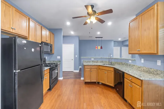 a kitchen with stainless steel appliances granite countertop a refrigerator a sink dishwasher a stove with wooden cabinets and floor