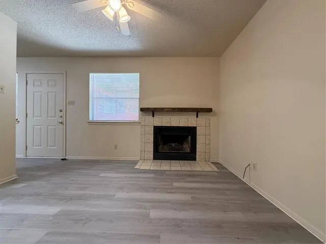 a view of an empty room with a fireplace and a window