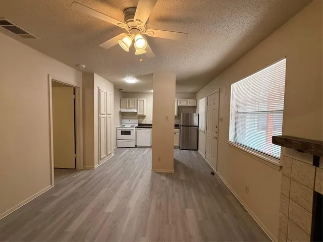 a view of a kitchen with a refrigerator a ceiling fan and wooden floor