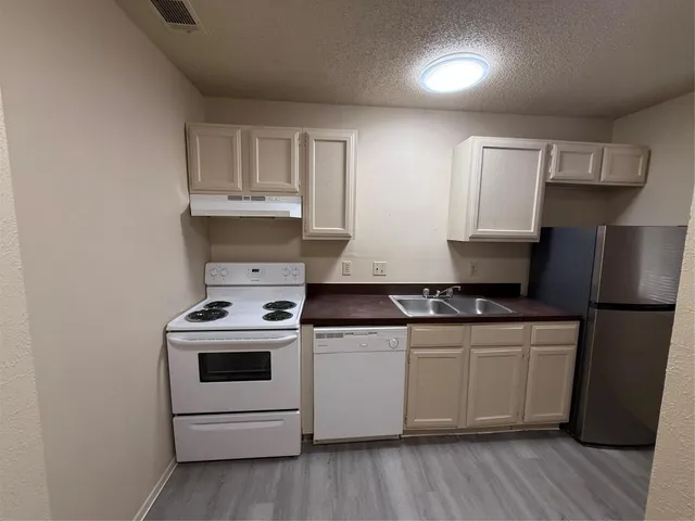 a kitchen with stainless steel appliances granite countertop a stove a sink and a refrigerator