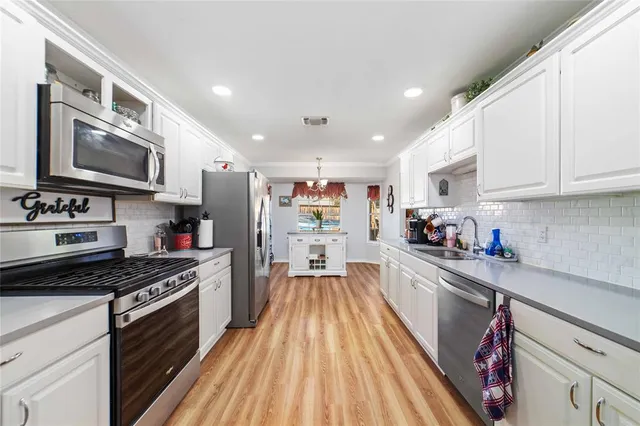 a kitchen with wooden floor and stainless steel appliances