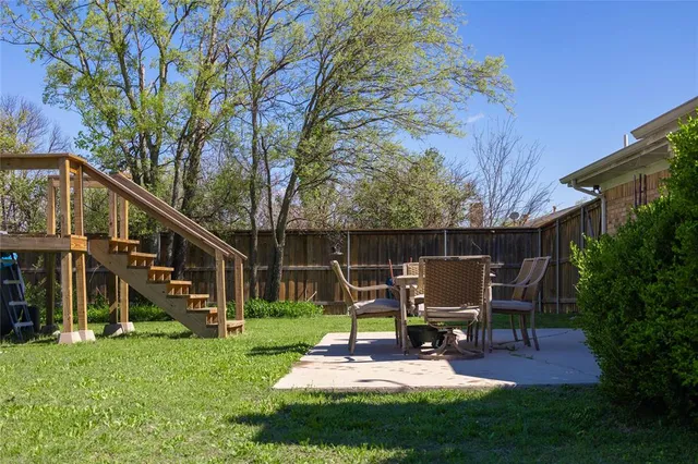 a view of a chair and table in backyard of the house