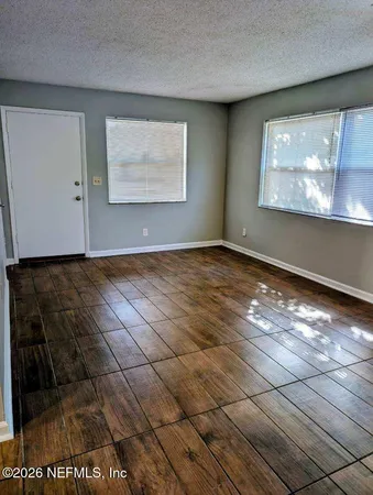 a view of an empty room with window and wooden floor