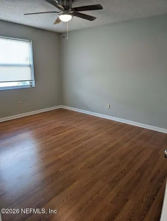 an empty room with wooden floor fan and windows