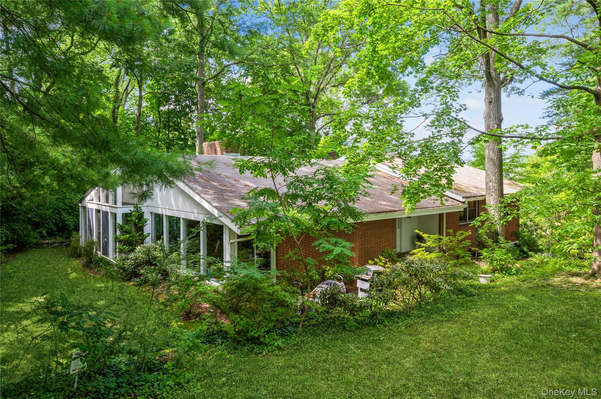 Rear view of house with brick siding, roof with shingles, and a yard