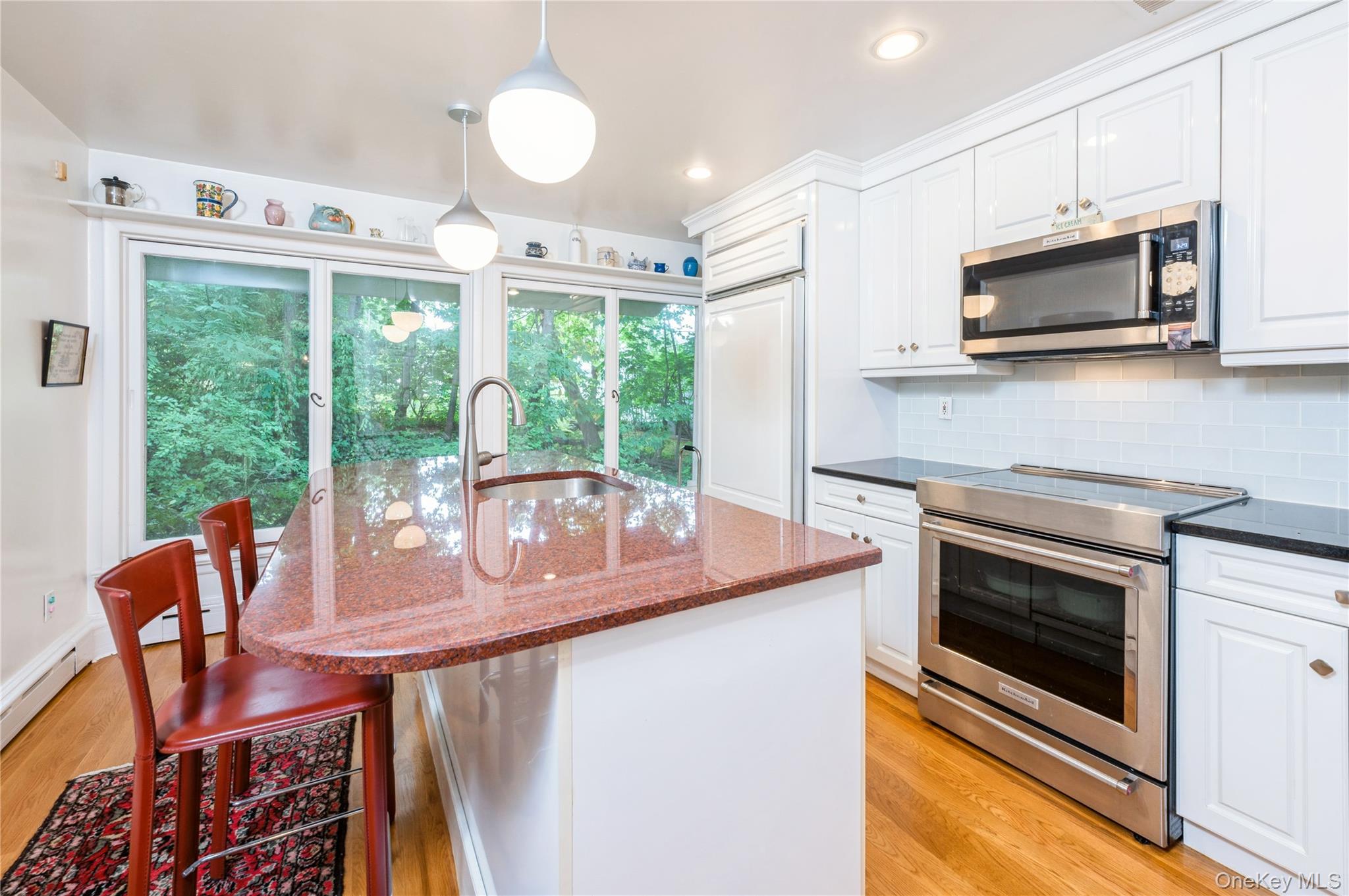 160 Hampshire Road Bronxville, NY 10708 - Photo 17 of 36 a kitchen with stainless steel appliances granite countertop a stove a microwave a sink a dining table and chairs with the floor