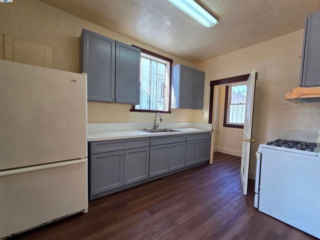 a kitchen with a refrigerator a sink and wooden floor