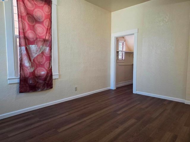 a view of an empty room with wooden floor and a painting
