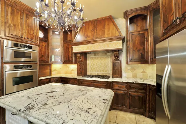 a kitchen with stainless steel appliances granite countertop a refrigerator a stove and a sink with wooden floor