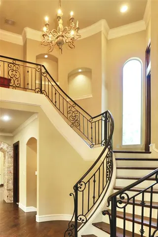 a view of staircase with railing and a chandelier