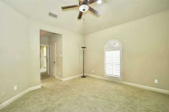 a view of empty room with a window and a ceiling fan