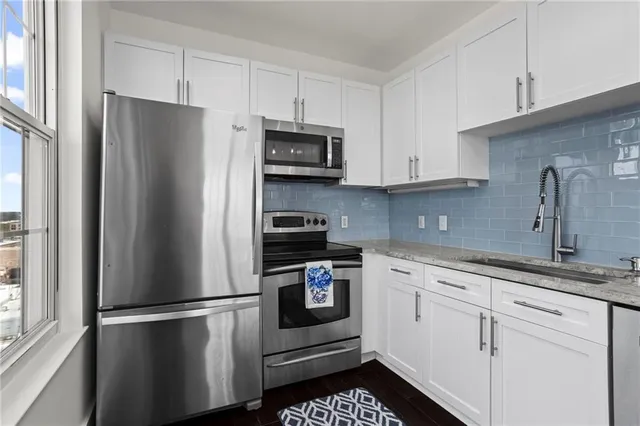 a kitchen with stainless steel appliances white cabinets and a refrigerator