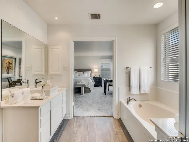 a bathroom with a tub a double vanity sink and mirror