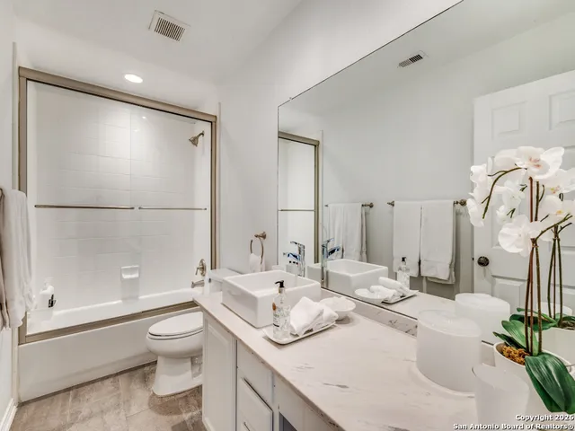 a bathroom with a granite countertop sink mirror vanity and toilet