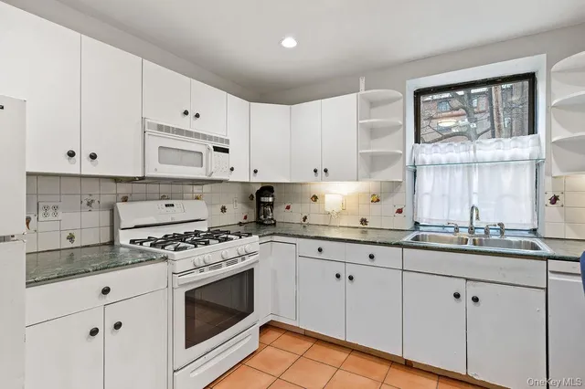 a kitchen with granite countertop white cabinets and white stainless steel appliances