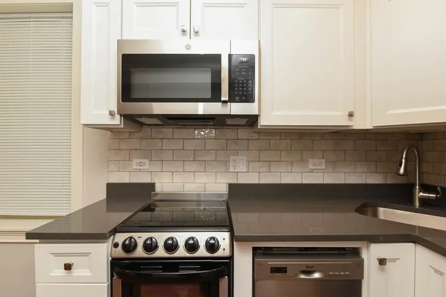 a kitchen with granite countertop a stove top oven microwave and cabinets