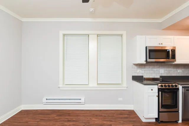 a view of kitchen with granite countertop white cabinets and stainless steel appliances