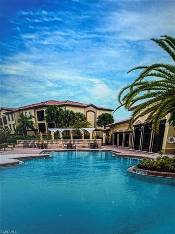 12970 Positano Circle, Unit 106 Naples, FL 34105 - Photo 2 of 5 a view of a swimming pool with lawn chairs and plants