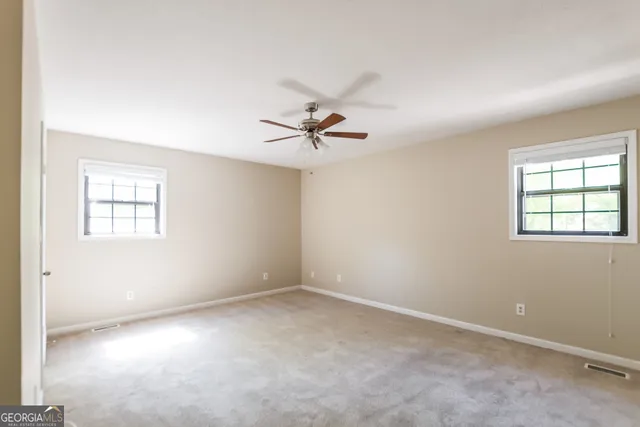 an empty room with a window and a fan