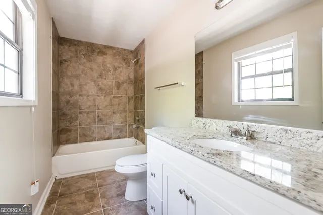 a bathroom with a granite countertop sink a toilet and shower