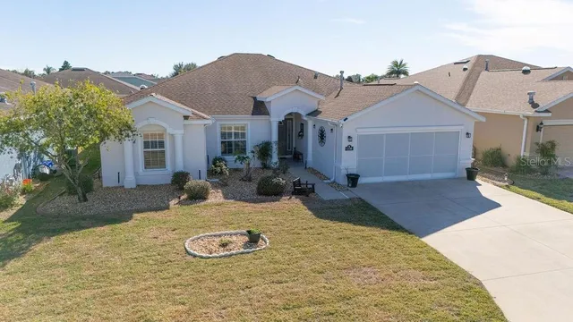front view of house with a yard and large tree