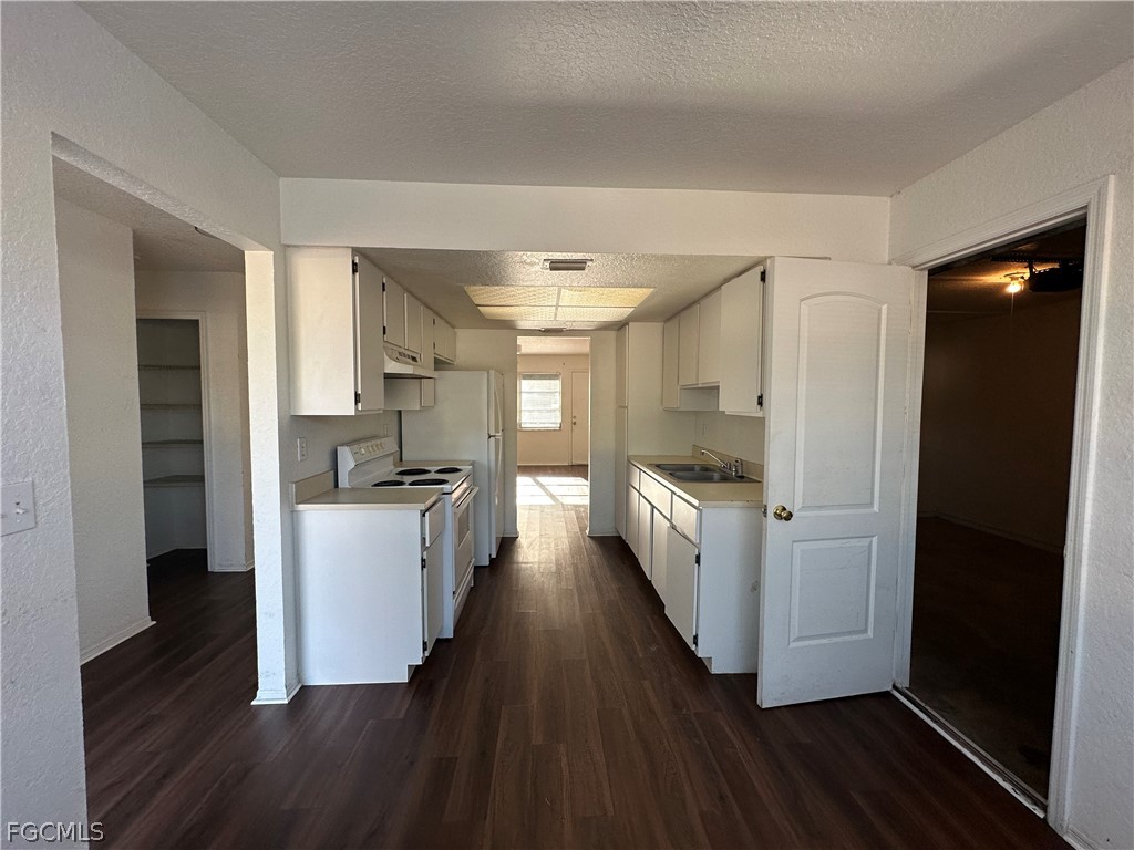 2429 George Avenue South, Unit 2431 Lehigh Acres, FL 33973 - Photo 4 of 16 a kitchen with a refrigerator and white cabinets