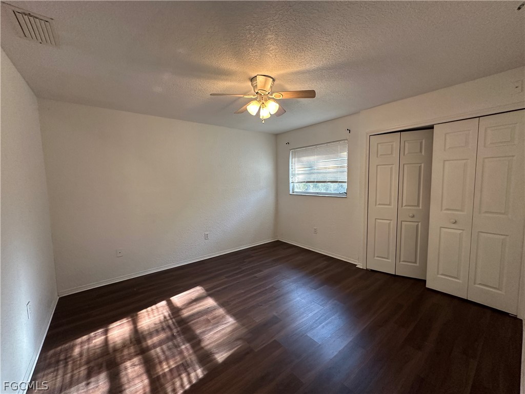 2429 George Avenue South, Unit 2431 Lehigh Acres, FL 33973 - Photo 9 of 16 an empty room with wooden floor chandelier fan and windows