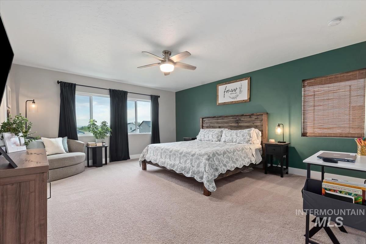 815 Knowledge Street Middleton, ID 83644 - Photo 24 of 49 Expansive room featuring a paneled wood headboard, large window with dark drapes, ceiling fan light fixture, and a bold accent wall