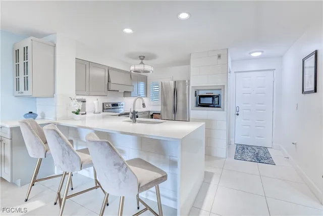 a kitchen with stainless steel appliances a sink a stove a refrigerator cabinets and chairs