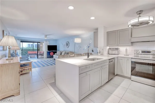 a kitchen that has a lot of white cabinets and stainless steel appliances