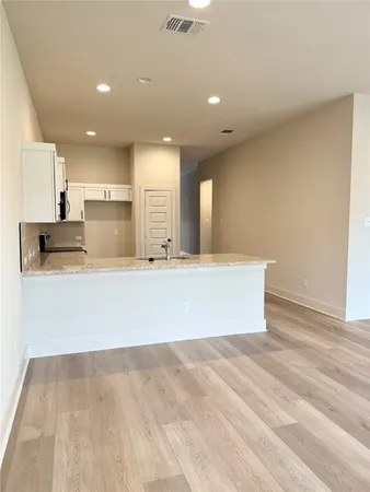 a view of kitchen with kitchen island stainless steel appliances wooden floor and living room view