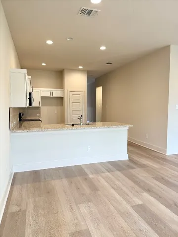 a view of kitchen with kitchen island a sink wooden floor and a counter top space