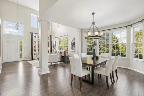 a dining room with wooden floor a chandelier a glass table and chairs