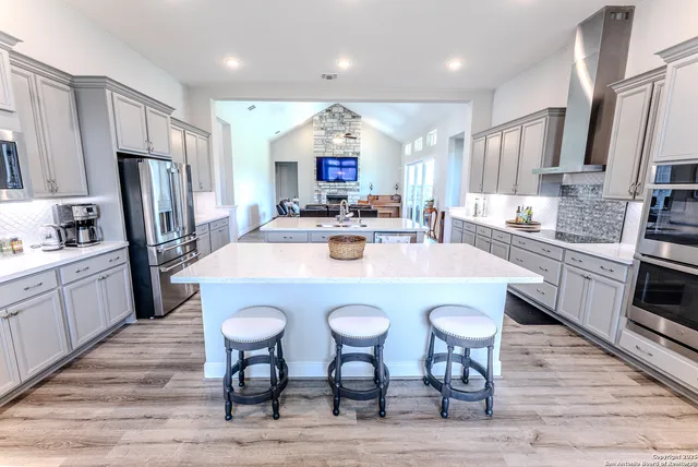 a kitchen with stainless steel appliances a dining table chairs refrigerator and microwave