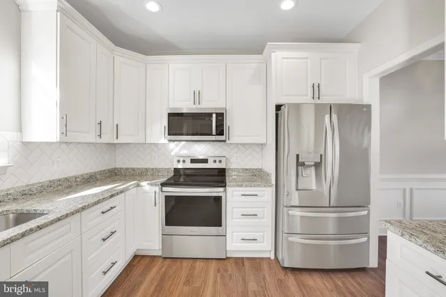 a kitchen with granite countertop white cabinets and white appliances