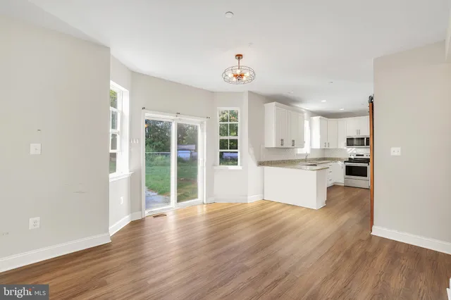 an empty room with wooden floor fireplace and a ceiling fan