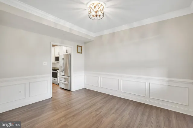 a view of an empty room with wooden floor and window