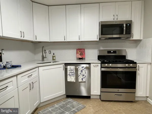 a kitchen with stainless steel appliances granite countertop white cabinets and stove top oven