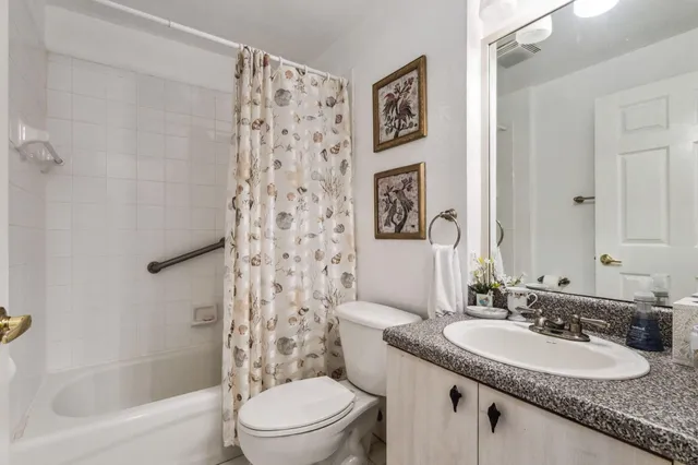 a bathroom with a granite countertop sink a toilet and shower