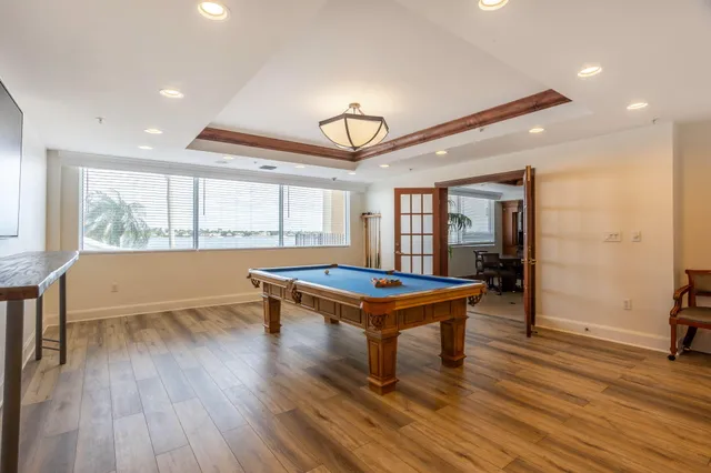a room with furniture pool table wooden floor and windows