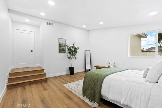 a bedroom with a bed and a potted plant on the dresser