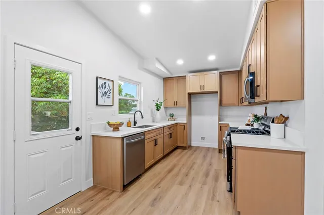 a kitchen with cabinets wooden floor and stainless steel appliances
