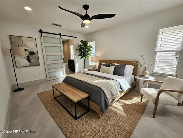 a bedroom with a bed a couch and potted plant