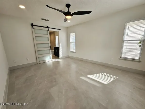 an empty room with windows and fan