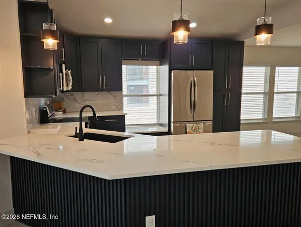 a kitchen with kitchen island granite countertop wooden cabinets and a refrigerator