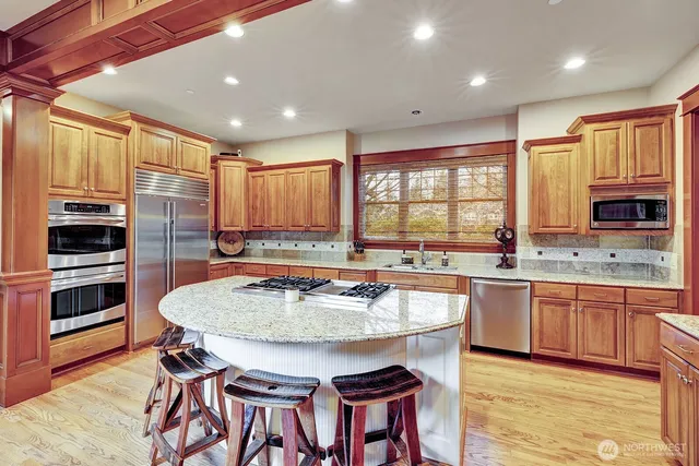 a kitchen with stainless steel appliances granite countertop a kitchen island hardwood floor sink stove and granite counter top
