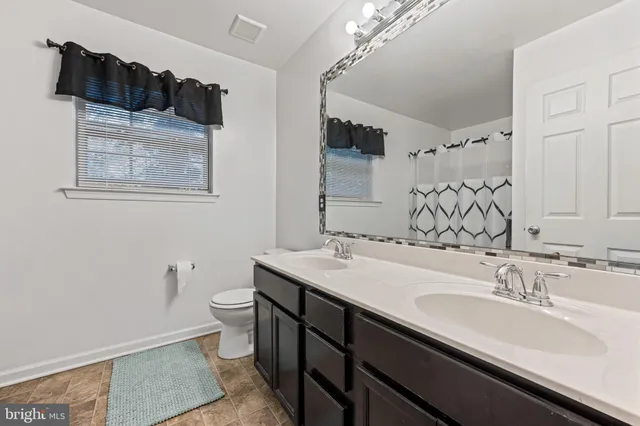 a bathroom with a sink double vanity granite and a toilet