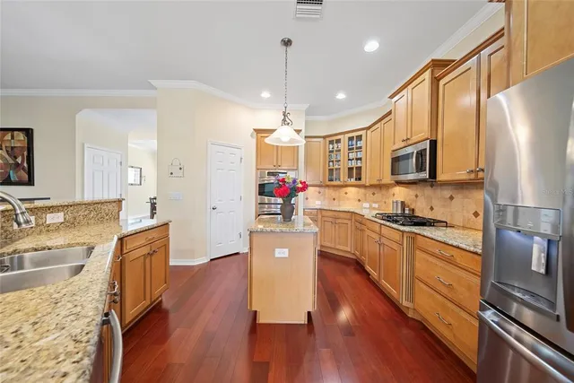 a large kitchen with stainless steel appliances granite countertop a stove refrigerator and a wooden floor