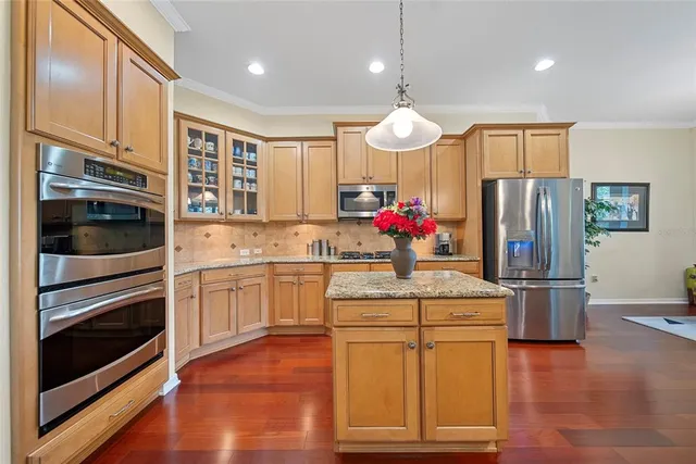 a kitchen with stainless steel appliances kitchen island granite countertop a refrigerator oven stove a sink and dishwasher with wooden floor