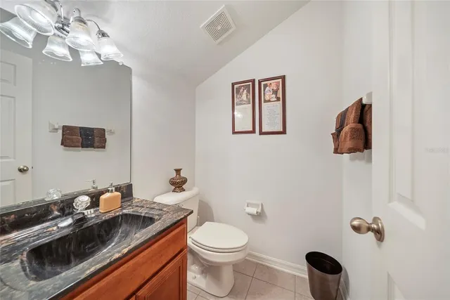 a bathroom with a granite countertop toilet a sink and mirror